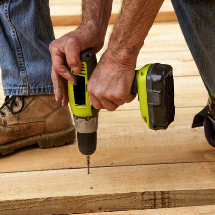 Power ToolsA person in jeans and work boots uses a green cordless drill to drive a screw into wooden planks, conveying a sense of focus and craftsmanship.